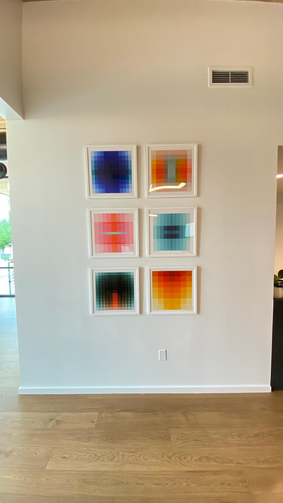 Six framed abstract pixel-pattern prints arranged in a grid on a residential wall